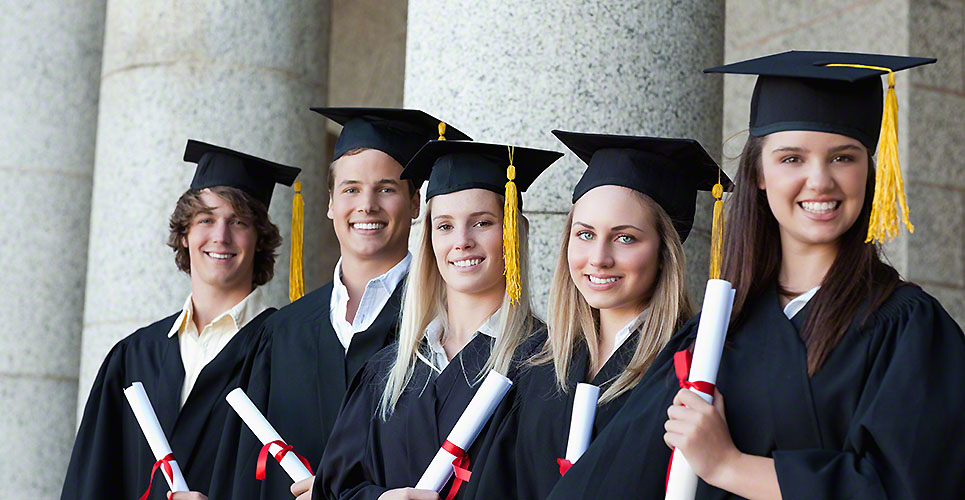 Smiling graduates posing in single line with columns in background