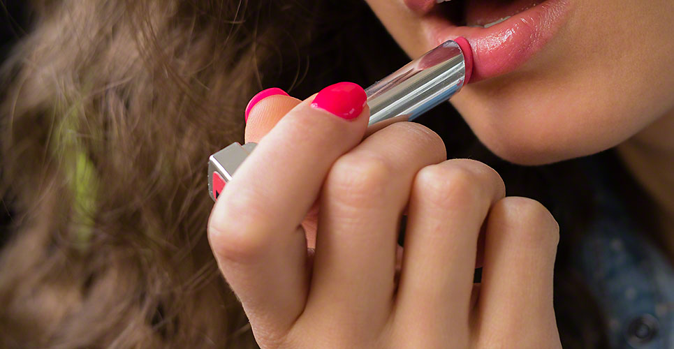 Young woman applies lipstick close-up